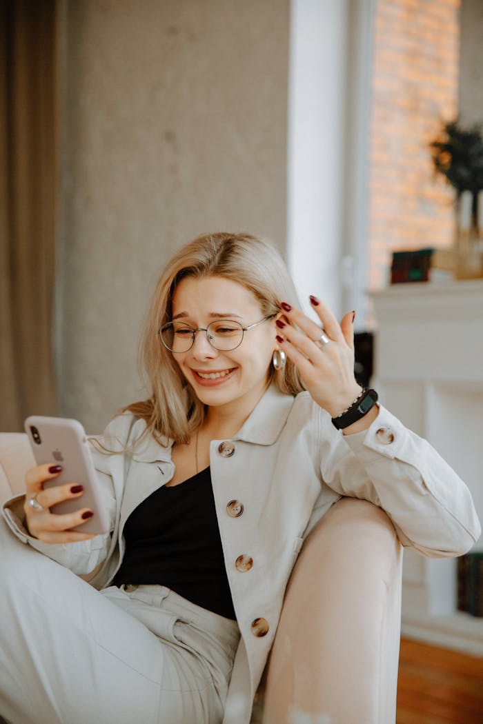 A woman indoors reacts emotionally while reading a message on her smartphone.